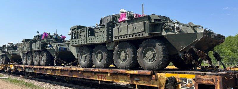 Open top railcars loaded with hi wide military vehicles